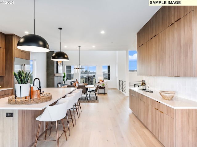 kitchen featuring light hardwood / wood-style flooring, sink, light stone countertops, pendant lighting, and appliances with stainless steel finishes