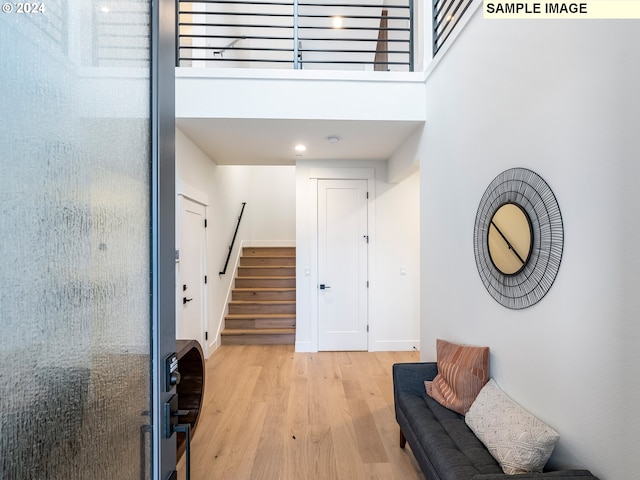 interior space featuring a towering ceiling and light wood-type flooring