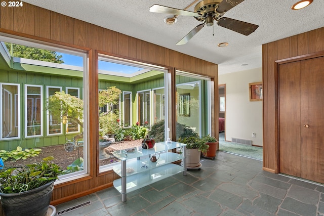 sunroom / solarium featuring a wealth of natural light, visible vents, and a ceiling fan