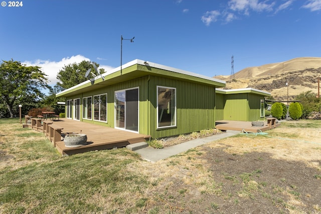 view of side of property with a deck with mountain view and a lawn