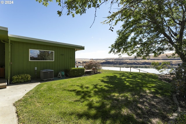 view of yard with a water view and central air condition unit