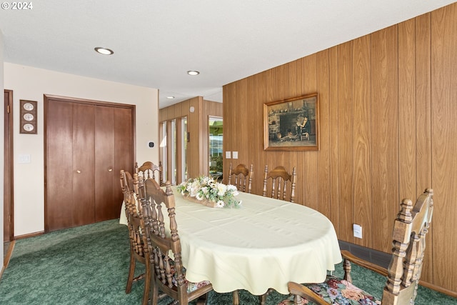 carpeted dining area featuring wood walls