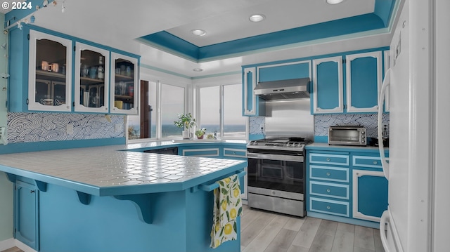 kitchen featuring white refrigerator, stainless steel stove, kitchen peninsula, light hardwood / wood-style flooring, and extractor fan