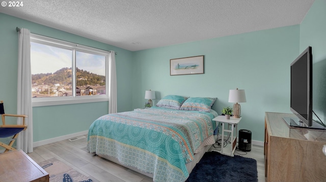 bedroom featuring a textured ceiling and light hardwood / wood-style floors