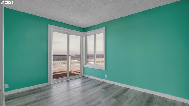 spare room with a textured ceiling and light wood-type flooring