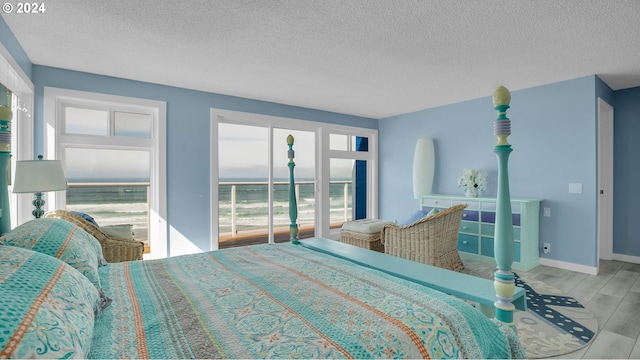 bedroom featuring a textured ceiling, light hardwood / wood-style floors, and a water view