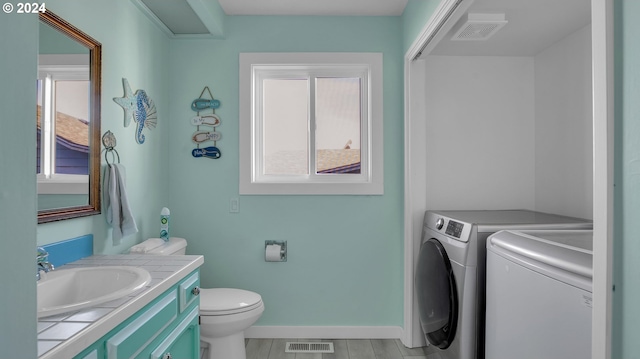 bathroom featuring toilet, vanity, and washing machine and dryer