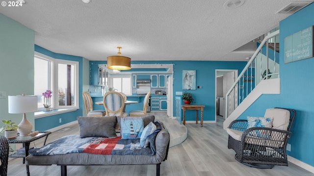 living room with light wood-type flooring and a textured ceiling