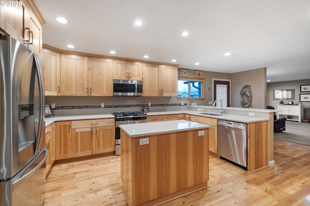 kitchen with kitchen peninsula, stainless steel appliances, a kitchen island, and sink