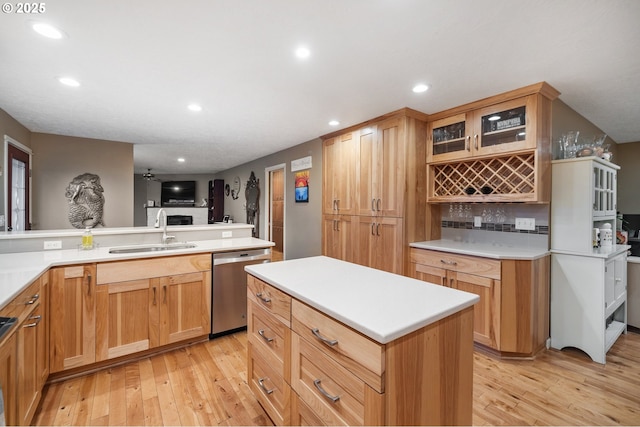 kitchen with a center island, sink, stainless steel dishwasher, ceiling fan, and kitchen peninsula