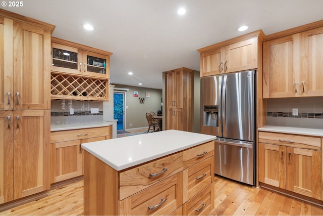 kitchen featuring decorative backsplash, stainless steel fridge, a kitchen island, and light hardwood / wood-style floors