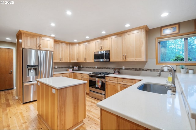 kitchen with light brown cabinetry, sink, a kitchen island, and stainless steel appliances