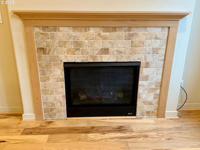 details with hardwood / wood-style flooring and a tiled fireplace