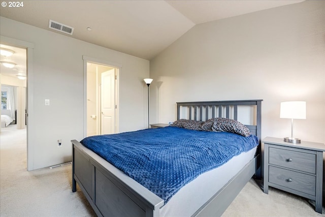 carpeted bedroom featuring ensuite bath and vaulted ceiling