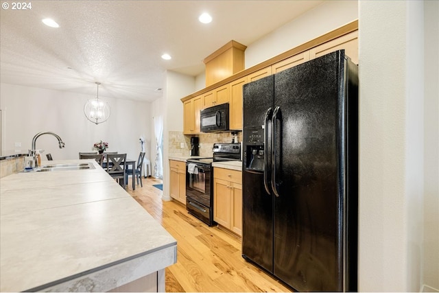 kitchen featuring sink, black appliances, light brown cabinets, and light hardwood / wood-style floors