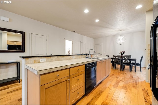 kitchen with sink, black dishwasher, an island with sink, a chandelier, and decorative light fixtures