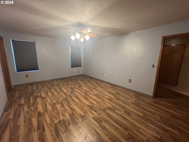 spare room featuring a textured ceiling, ceiling fan, and dark wood-type flooring