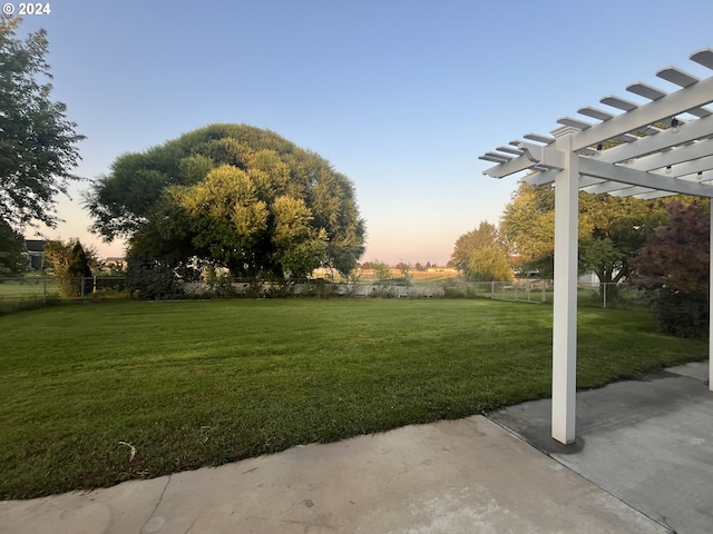 yard at dusk featuring a pergola and a patio area