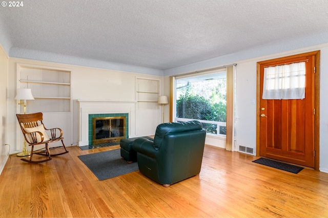 living room featuring a tiled fireplace, hardwood / wood-style flooring, and a textured ceiling