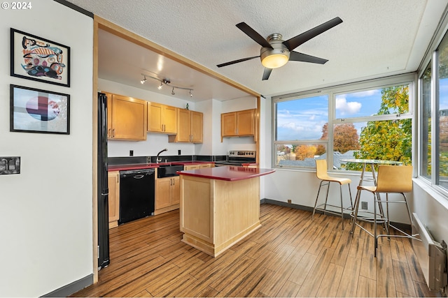 kitchen with black dishwasher, light wood-type flooring, a textured ceiling, and a kitchen island