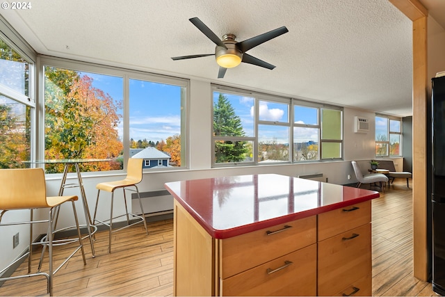 1220 NE 17th Ave Unit 4C, Portland, OR 97232 - kitchen with a textured ceiling, light wood-style floors, a ceiling fan, freestanding refrigerator, and open floor plan