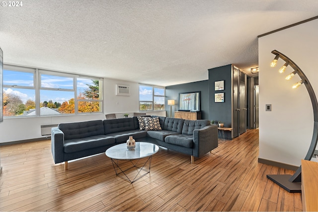 living room with light wood-type flooring, a textured ceiling, and an AC wall unit