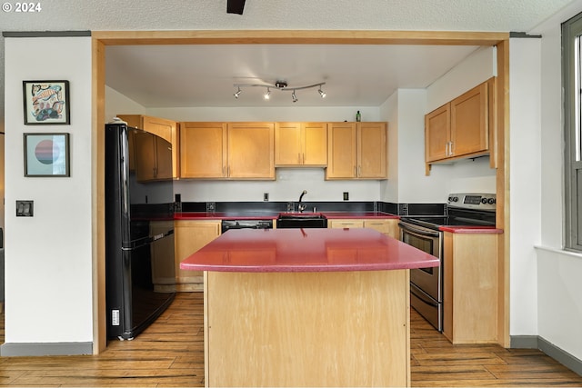 kitchen featuring light hardwood / wood-style floors, stainless steel range with electric stovetop, a kitchen island, and black refrigerator