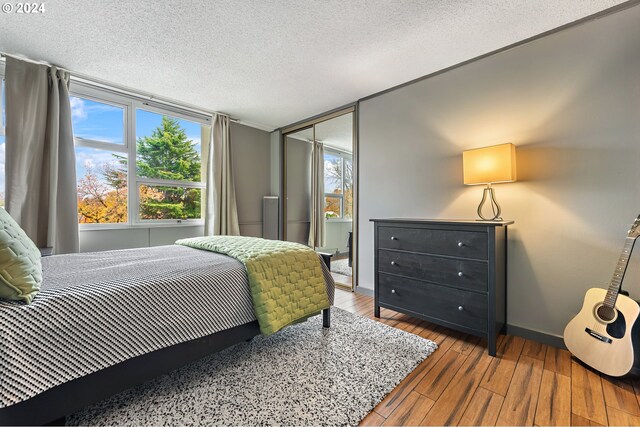 bedroom with a closet, a textured ceiling, and hardwood / wood-style flooring