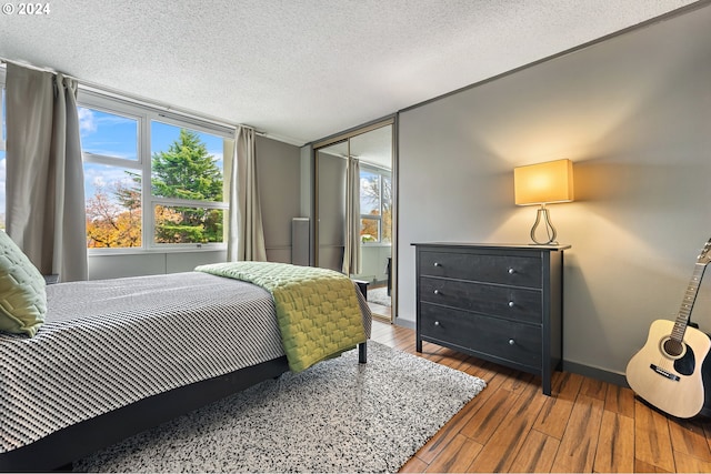 1220 NE 17th Ave Unit 4C, Portland, OR 97232 - bedroom with hardwood / wood-style flooring, baseboards, a textured ceiling, and multiple windows