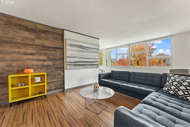 living room with wood walls, wood-type flooring, and a textured ceiling