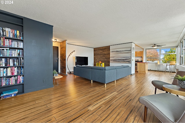 living room with hardwood / wood-style floors, ceiling fan, and a textured ceiling