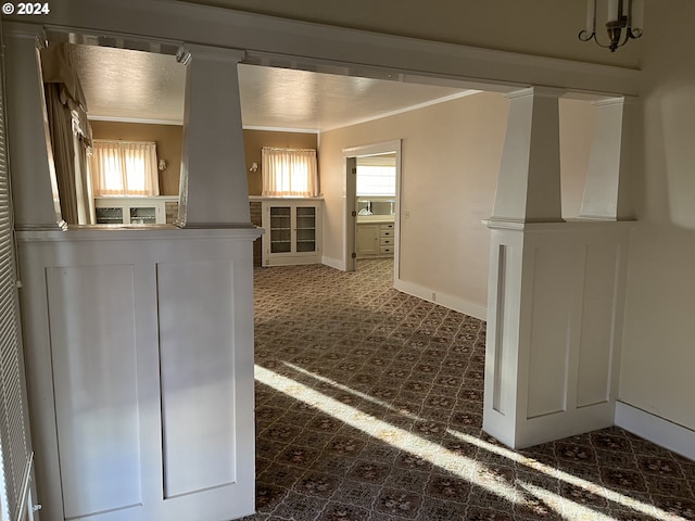 interior space with dark carpet, crown molding, and decorative columns