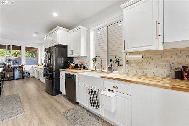 kitchen with decorative backsplash, white cabinetry, dishwasher, and wooden counters