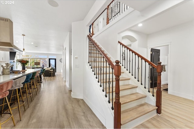 stairway with bar area and hardwood / wood-style floors