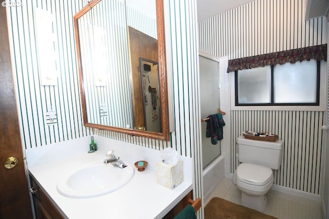 full bathroom featuring tile patterned floors, vanity, toilet, and bath / shower combo with glass door