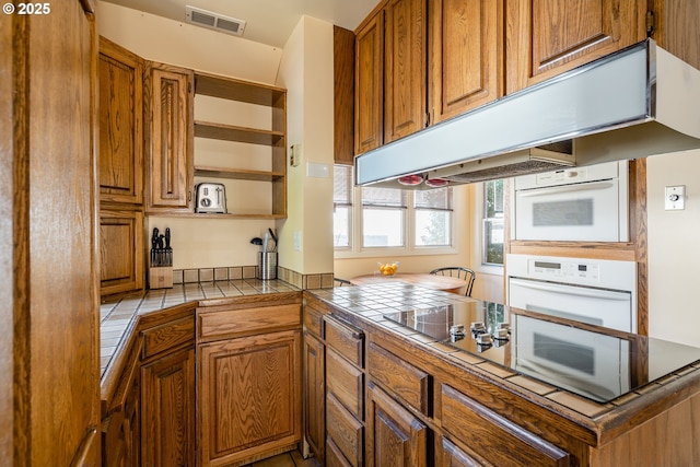 kitchen with tile counters, oven, and kitchen peninsula