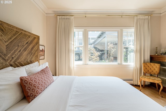 bedroom with hardwood / wood-style flooring, ornamental molding, and baseboard heating