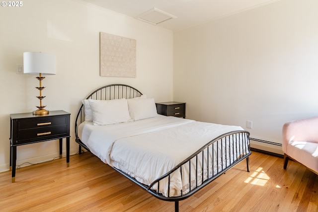 bedroom with a baseboard heating unit and light wood-type flooring