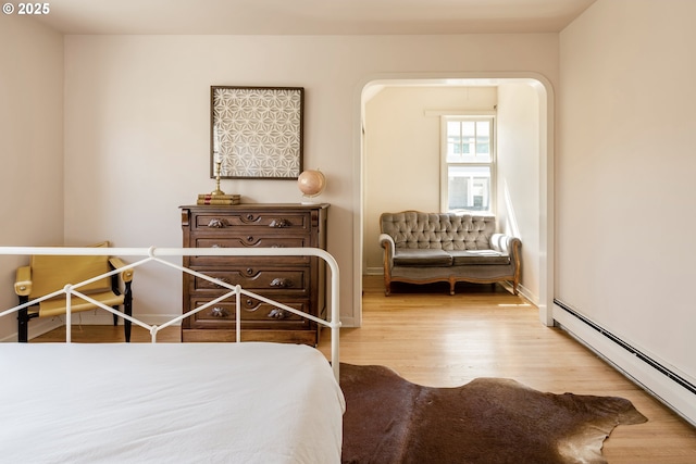 bedroom with hardwood / wood-style floors and a baseboard heating unit