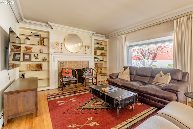 living room featuring crown molding, wood-type flooring, built in features, and a fireplace