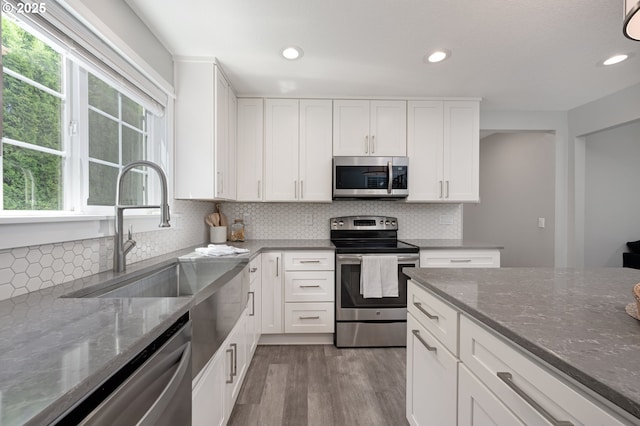 2823 SE Olsen St, Milwaukie, OR 97222 - kitchen with appliances with stainless steel finishes, wood finished floors, dark stone counters, recessed lighting, and white cabinets