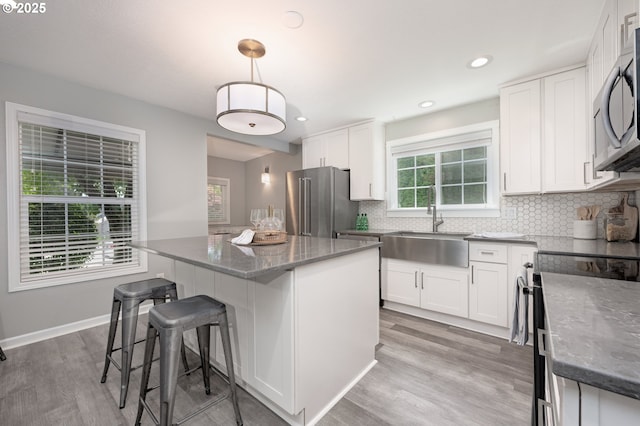 2823 SE Olsen St, Milwaukie, OR 97222 - kitchen with stainless steel appliances, a sink, dark stone counters, a center island, and white cabinets