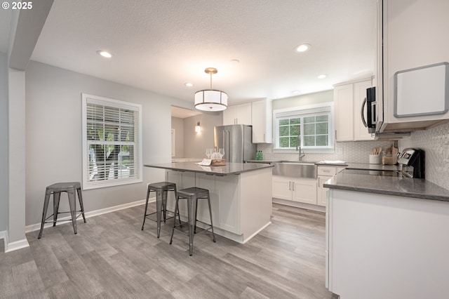 2823 SE Olsen St, Milwaukie, OR 97222 - kitchen featuring appliances with stainless steel finishes, a sink, decorative backsplash, light wood-type flooring, and white cabinetry