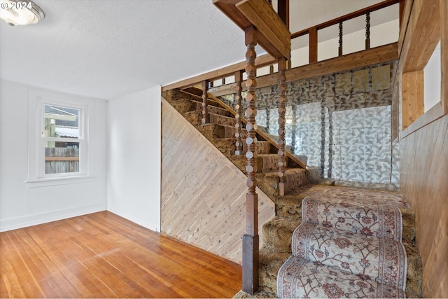 staircase featuring wood-type flooring and a textured ceiling