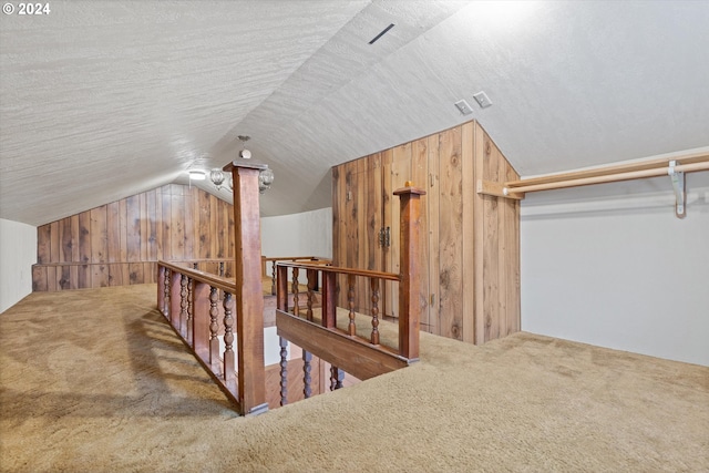 additional living space with vaulted ceiling, carpet floors, wood walls, and a textured ceiling