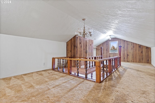 bonus room with a textured ceiling, vaulted ceiling, carpet flooring, and wooden walls