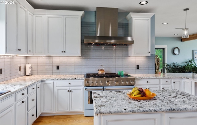 kitchen with white cabinets, wall chimney range hood, stainless steel stove, light wood-type flooring, and tasteful backsplash