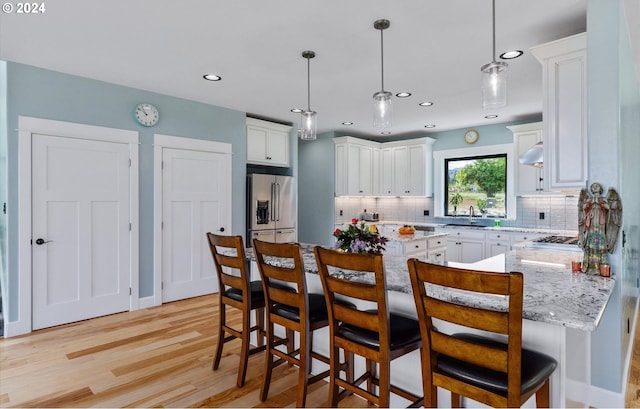 kitchen featuring white cabinetry, hanging light fixtures, appliances with stainless steel finishes, and light hardwood / wood-style flooring