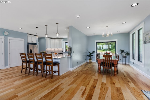 dining space with light wood-type flooring and a notable chandelier