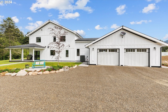 modern farmhouse featuring cooling unit, a garage, and a front lawn